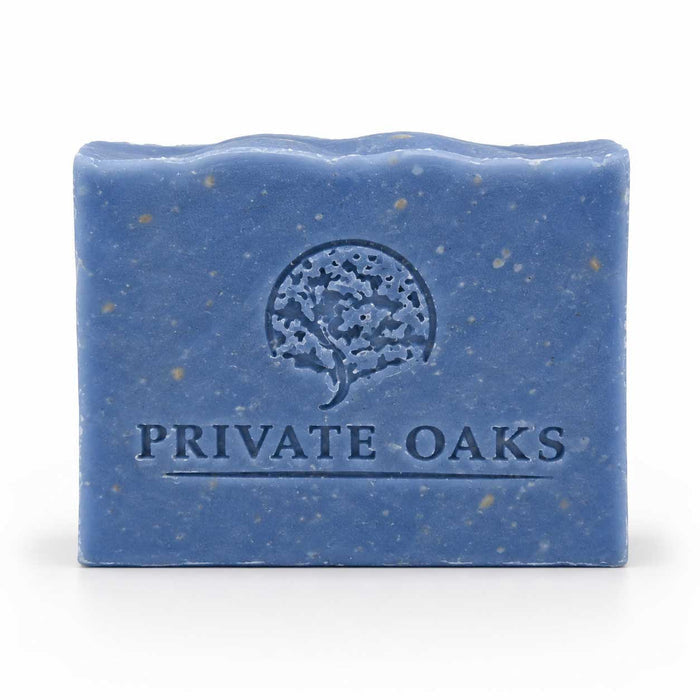 A rectangular blue bar of soap with visible speckles and an embossed tree logo and the words 'PRIVATE OAKS' on the front, photographed on a clean white background.