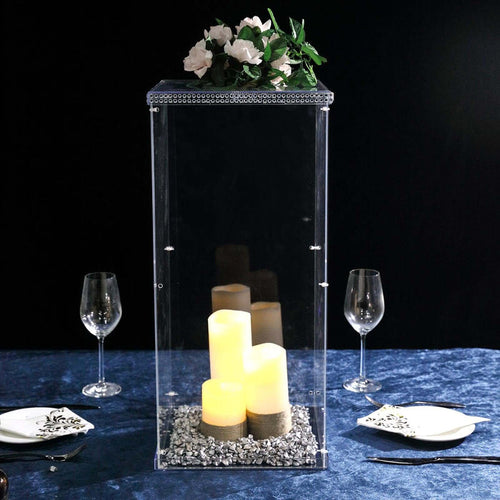 Elegant acrylic candle holder with decorative stones and faux flowers.