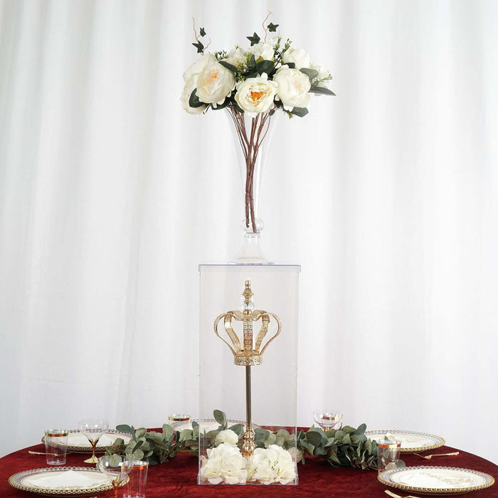 Crown display under glass with flowers on top, set on a dining table.