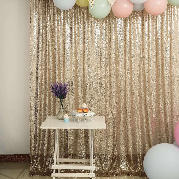 Decorative table with cupcakes and flowers against a shimmering backdrop.