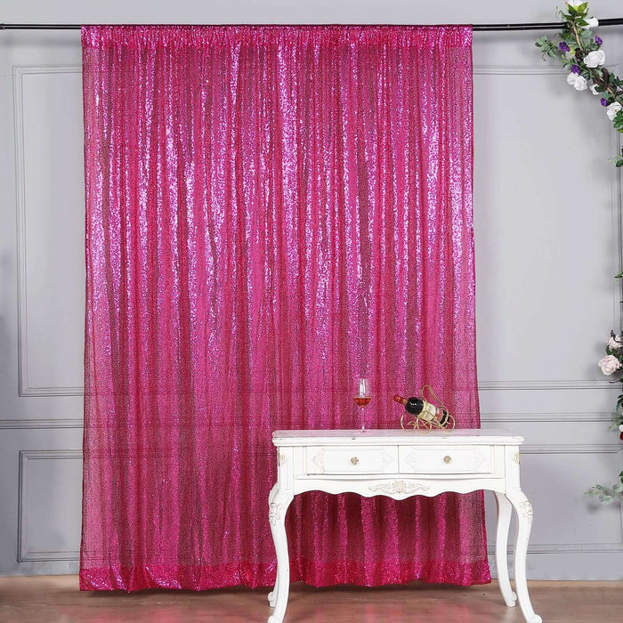 Shimmering pink sequin curtain draped on a rod with a decorative table in front.