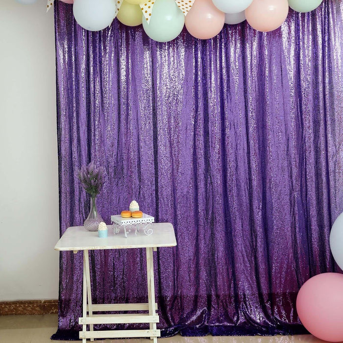 Purple sequin backdrop with balloons and a table set for a celebration.