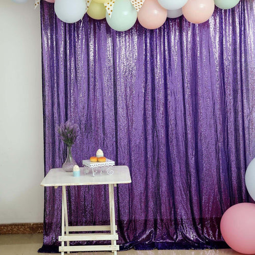 Purple sequin backdrop with balloons and a table set for a celebration.