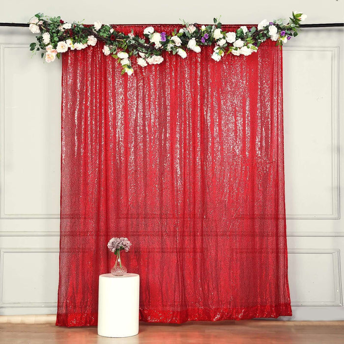 Red sequin backdrop with floral decoration for events and photo shoots.