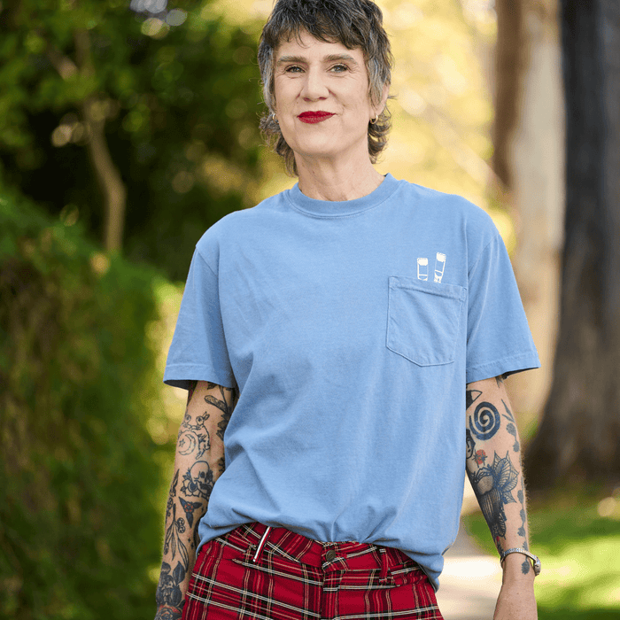 Woman wearing a blue t-shirt that has white pencil screen-printed graphics poking out of the pocket.