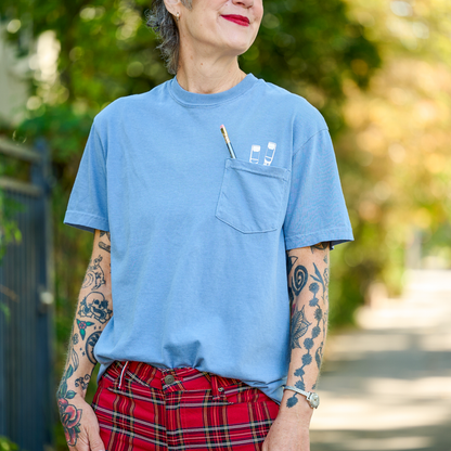 Woman wearing a blue t-shirt with a Blackwing 602 pencil poking out of the pocket.