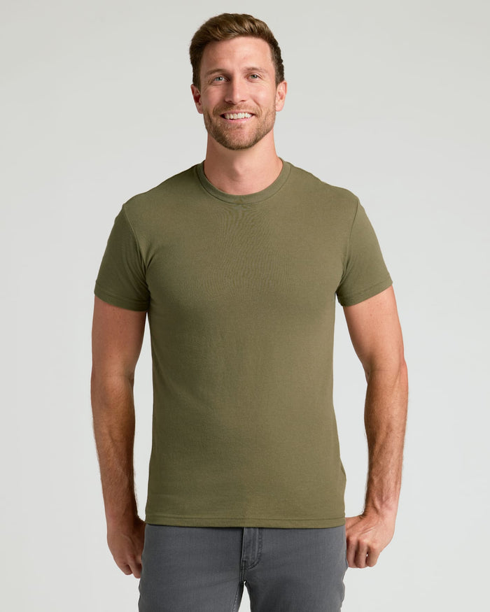 Man wearing Classic Crew Neck 6-Pack olive t-shirt, gray pants, smiling.