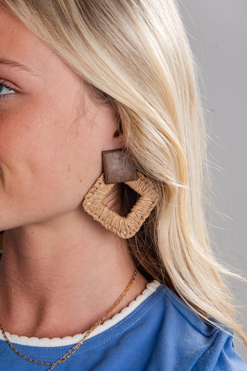 Close-up of a woman wearing a textured square earring with a blurred background