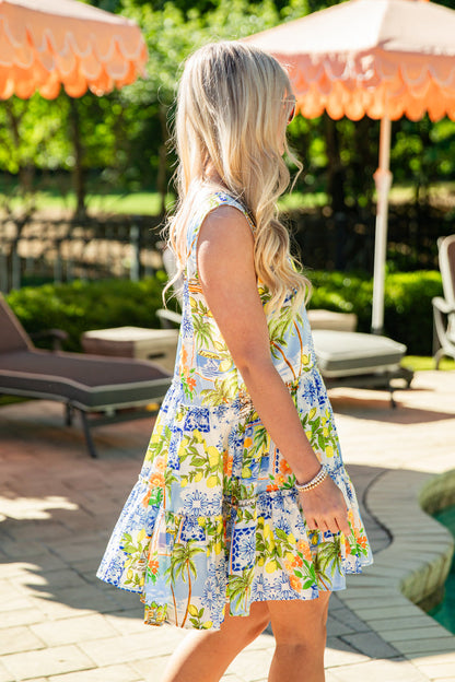 Woman in a colorful dress standing outdoors near a pool area with umbrellas.