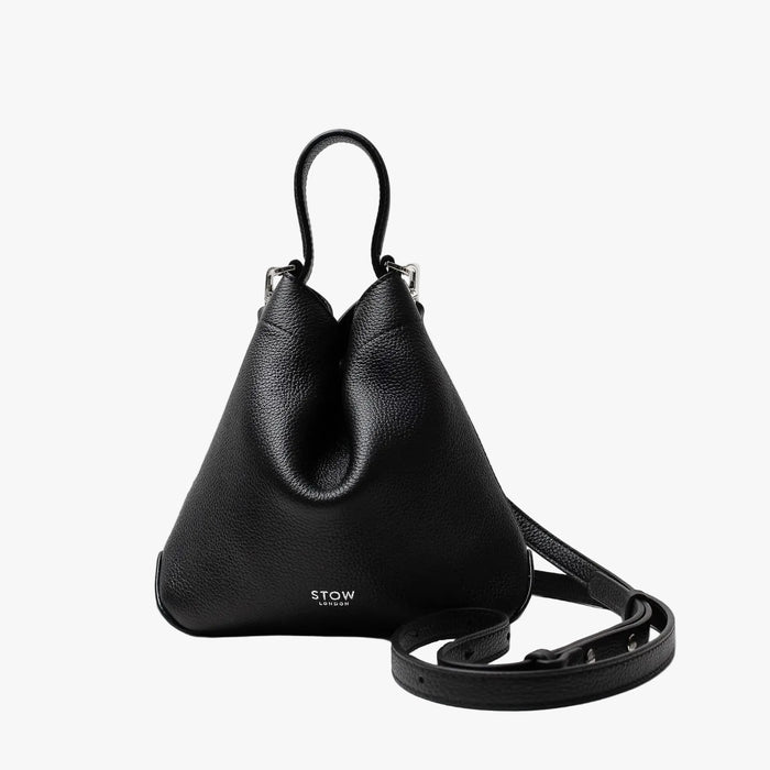 STOW London's Mini Curve in Black pebbled leather and detachable leather crossbody strap on a light grey background