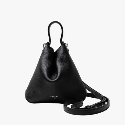 STOW London's Mini Curve in Black pebbled leather and detachable leather crossbody strap on a light grey background