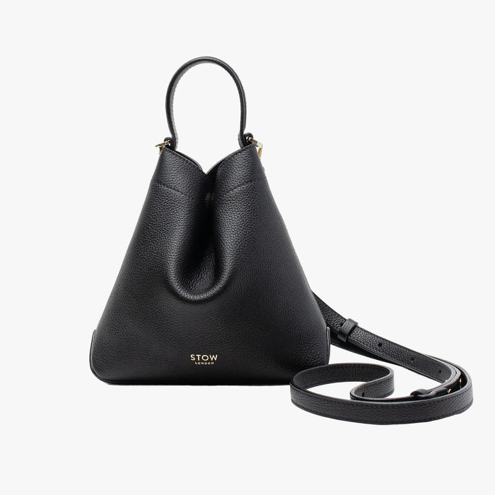 STOW London's Mini Curve in Black pebbled leather and detachable leather crossbody strap on a light grey background