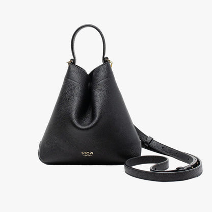 STOW London's Mini Curve in Black pebbled leather and detachable leather crossbody strap on a light grey background