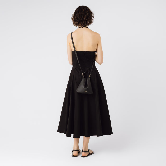 Model wearing STOW London's Mini Curve in Black pebbled leather with the detachable leather crossbody strap on a white background