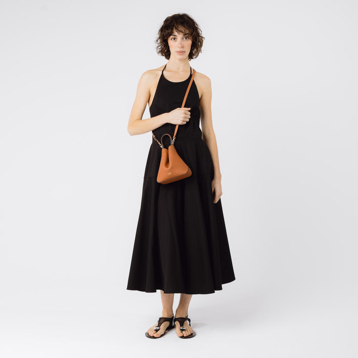 STOW London's Mini Curve in Earth Tan worn crossbody with detachable leather strap by model featuring gold-coated hardware on a white background