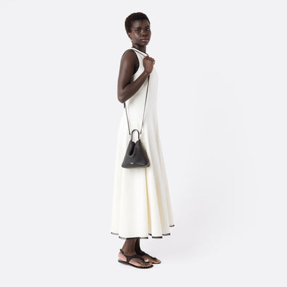 Model wearing STOW London's Mini Curve in Black pebbled leather with the detachable leather crossbody strap on her shoulder on a white background