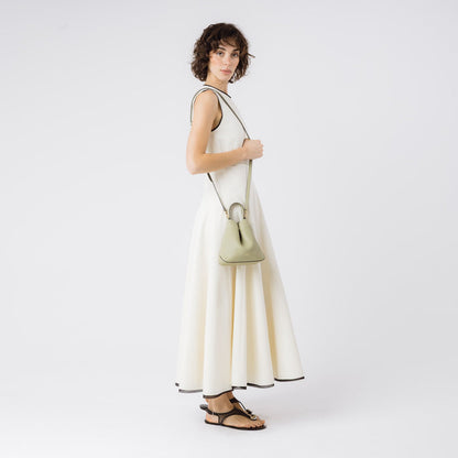 Model wearing STOW London's Mini Curve in Pale Green pebbled leather with the detachable leather crossbody strap on her shoulder on a white background