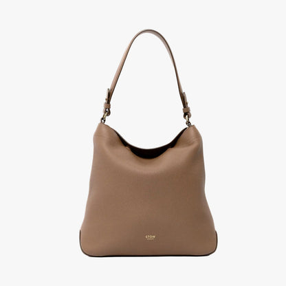 STOW London's Curve in Mocha leather on a light grey background featuring the detachable shoulder strap with gold hardware and details with the top handle tucked into the bag