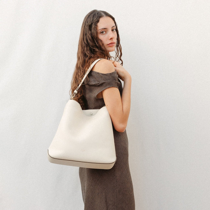 Model wearing STOW London's Curve in Spring Moon leather featuring the detachable shoulder strap with gold hardware and details
