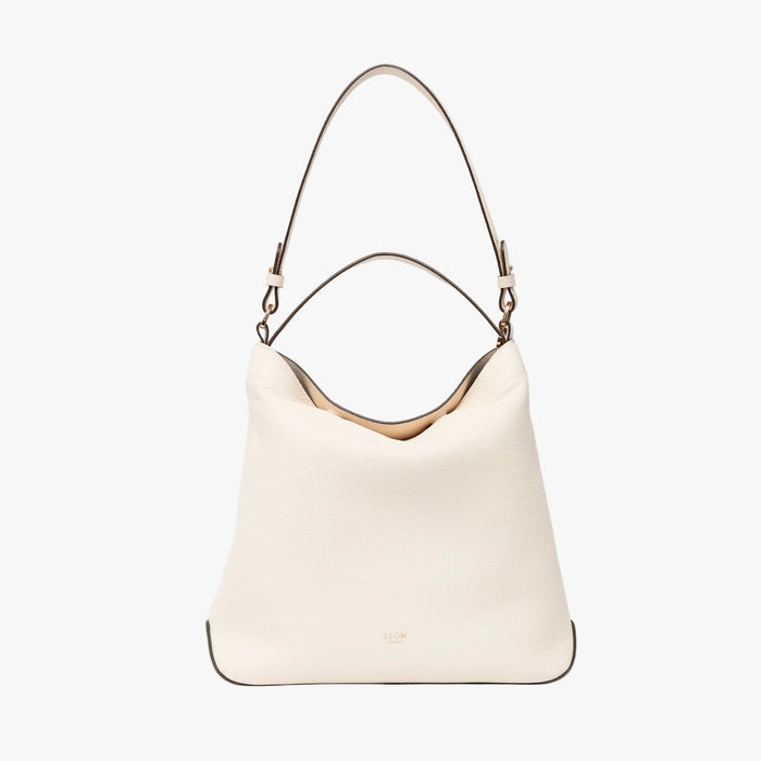 STOW London's Curve in Spring Moon leather on a light grey background featuring the detachable shoulder strap and top handle with gold hardware and details