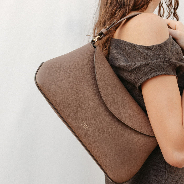 Model wearing STOW London's East West in Mocha leather featuring the detachable shoulder strap with gold hardware and details
