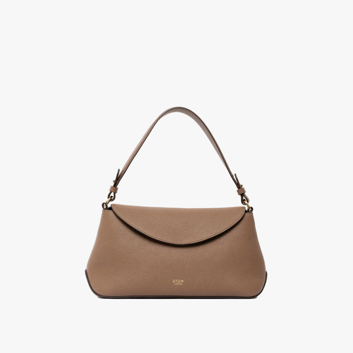 STOW London's East West bag in Mocha pebbled leather with the shoulder strap attached and top handle tucked into the bag featuring gold-coated stainless steel hardware on a light grey background