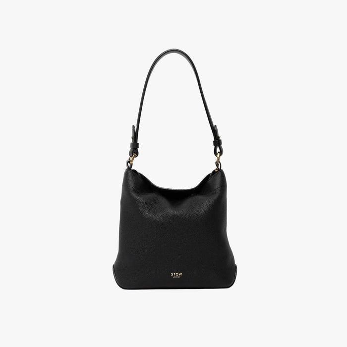 STOW London's Midi Curve and detachable shoulder strap in Black leather on a light grey background featuring gold hardware and details