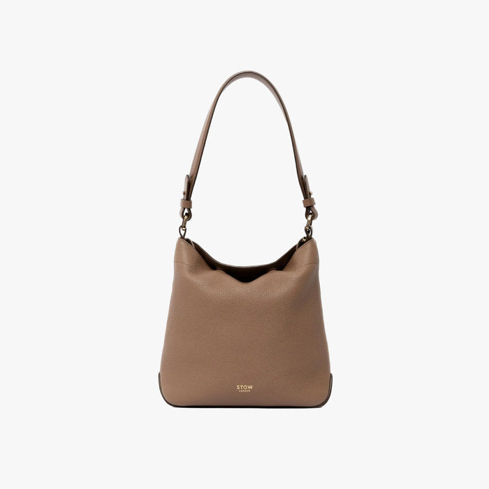 STOW London's Midi Curve and detachable shoulder strap in Mocha leather on a light grey background featuring gold hardware and details