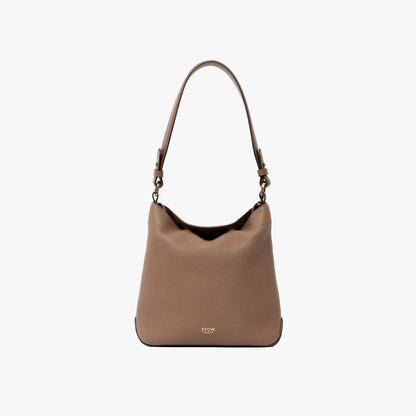 STOW London's Midi Curve and detachable shoulder strap in Mocha leather on a light grey background featuring gold hardware and details