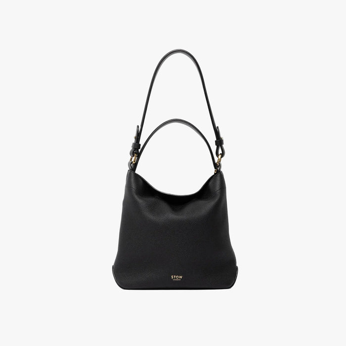 STOW London's Midi Curve and detachable shoulder strap and top handle in Black leather  out on a light grey background featuring gold hardware and details