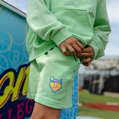 Youth model wearing green youth shorts with "Lemonade" design