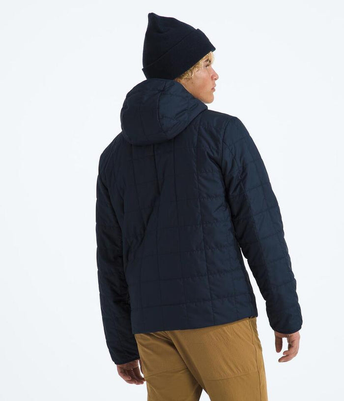 Person wearing a dark blue puffer jacket and black beanie on a white background