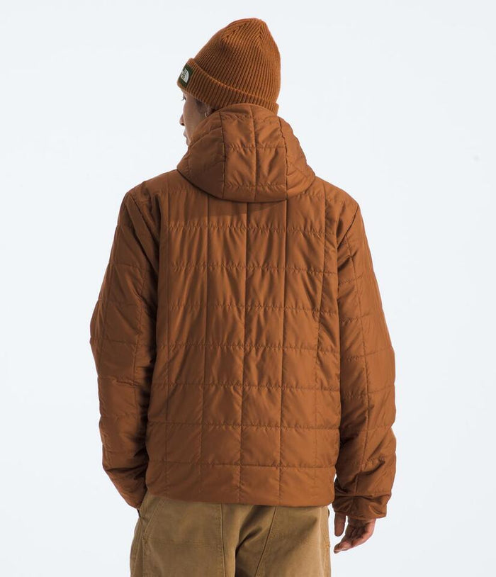 Person wearing a brown puffer jacket and beanie on a white background