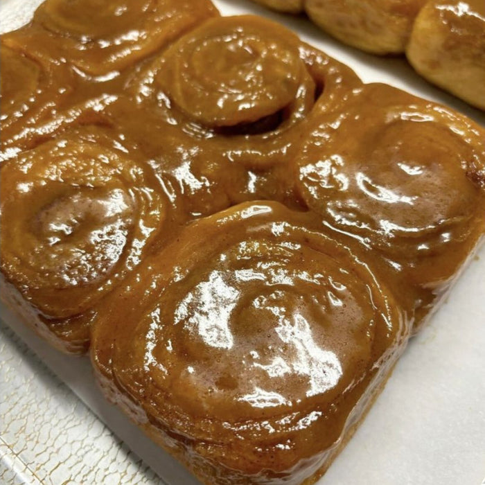 Caramel rolls with a glossy glaze on a white surface