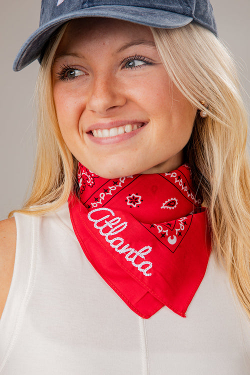 Woman wearing a red 'Atlanta' bandana and a denim cap against a neutral background