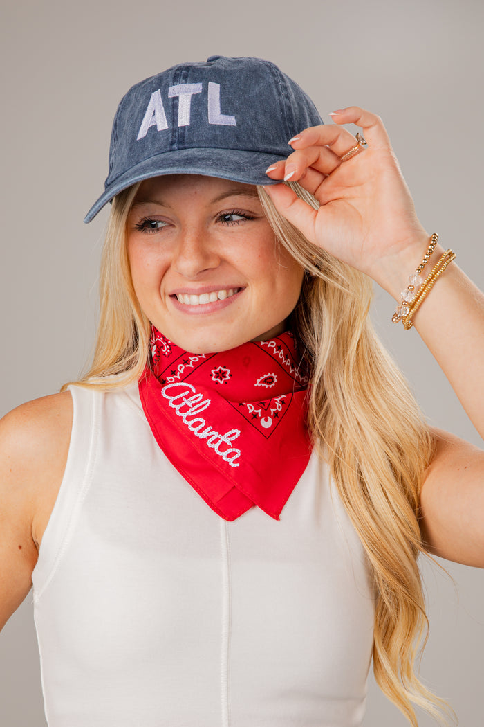 Woman wearing a denim cap with 'ATL' and a red bandana with 'Atlanta' text, against a neutral background.