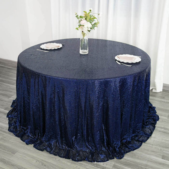 Navy blue sequin tablecloth on round table with floral centerpiece and plates.