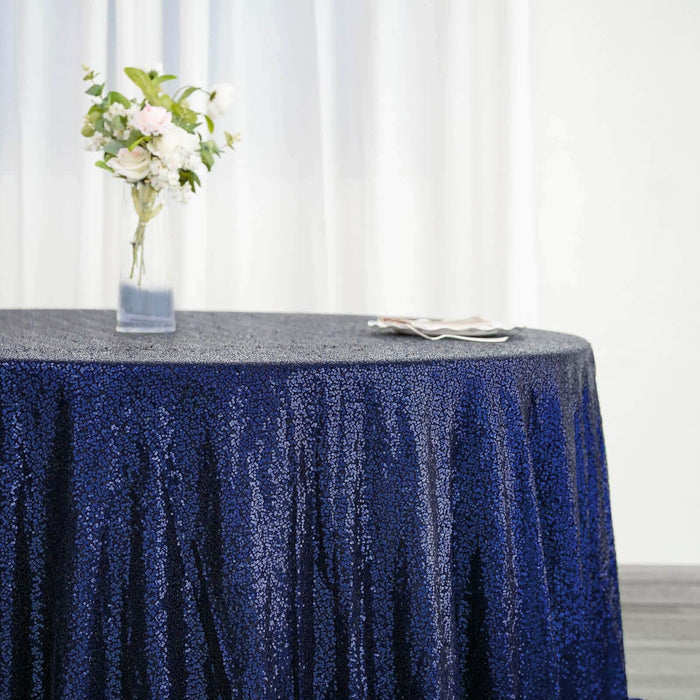 Navy sequin tablecloth draped over a round table with floral centerpiece