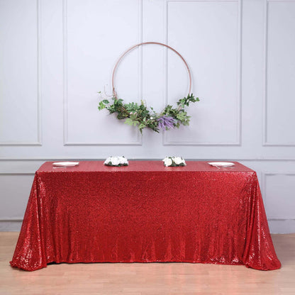 Red sequin tablecloth with floral arrangement and circular decor backdrop.