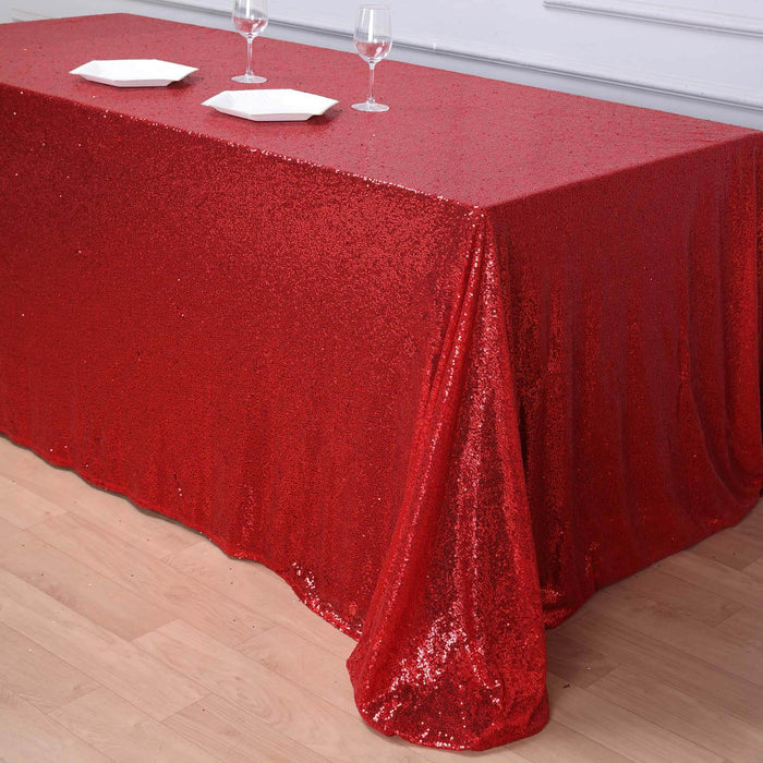 Red sequin tablecloth draped elegantly over a table with glasses and plates.