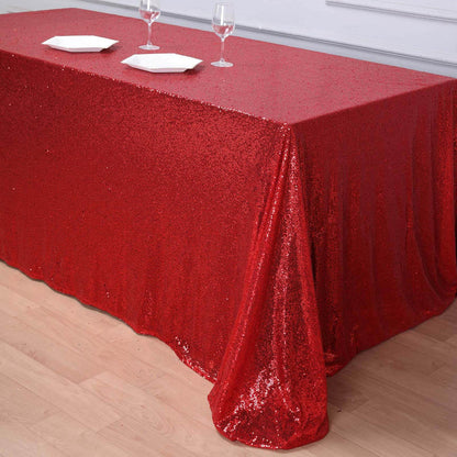 Red sequin tablecloth draped elegantly over a table with glasses and plates.