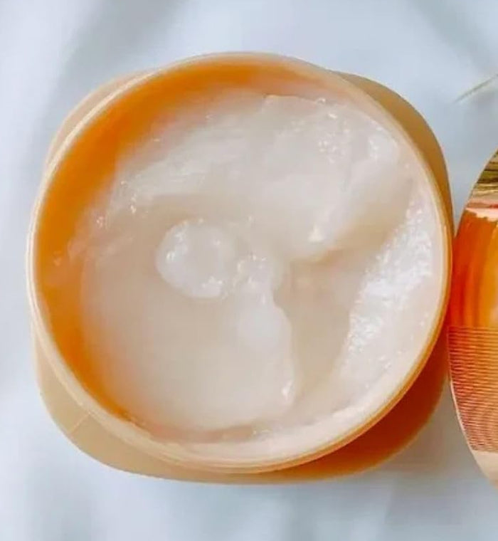 Open jar of cream with a gold lid on a light background