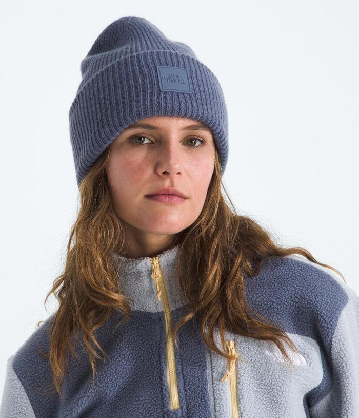 Person wearing a blue knit beanie and a matching fleece jacket on a white background