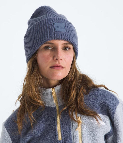 Person wearing a blue knit beanie and a matching fleece jacket on a white background