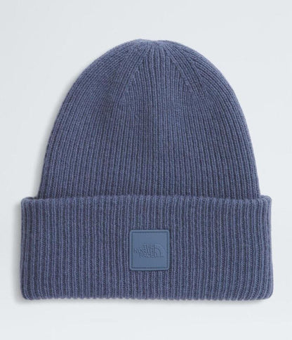 Blue knit beanie with a logo patch on a light gray background