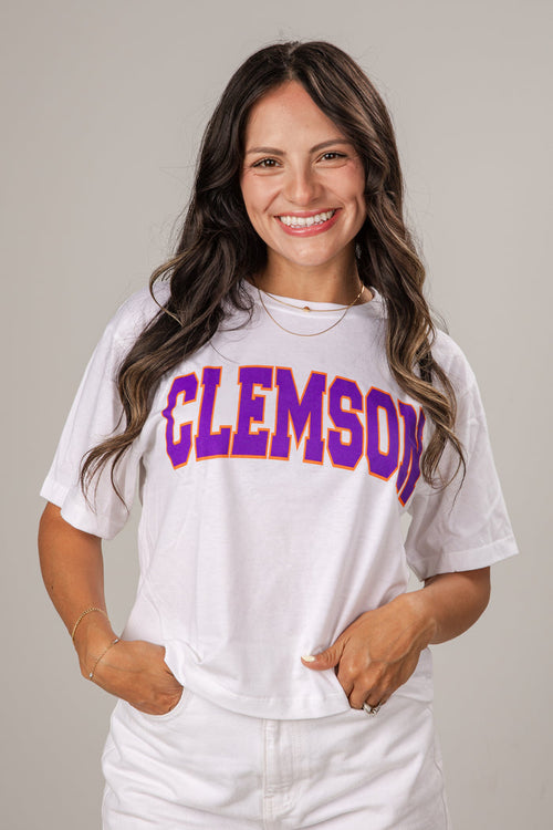 Woman wearing a white t-shirt with 'Clemson' printed in purple and yellow.