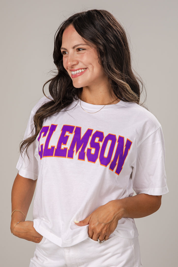 Woman wearing a white t-shirt with 'CLEMSON' printed on it against a plain background